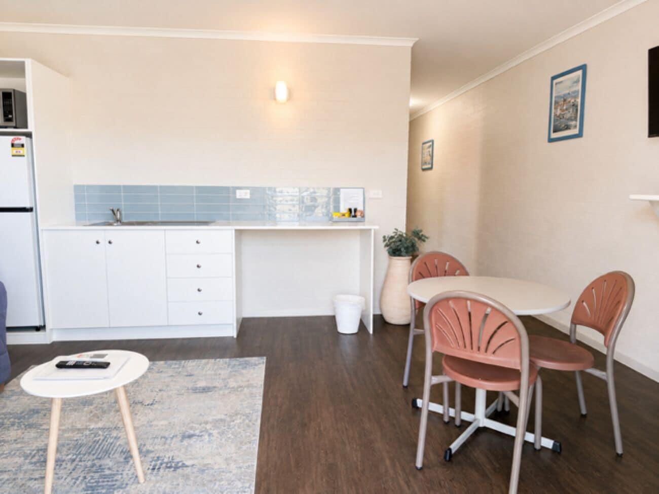 A compact kitchen with white cabinets, a countertop, and a small dining area with two chairs and a table.
