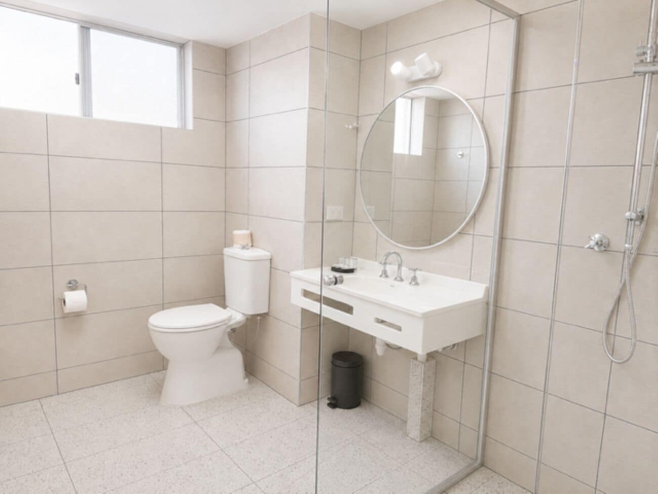 A modern bathroom with a toilet, sink, mirror, and shower.