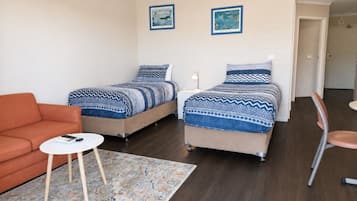 A bedroom with two beds, a sofa, a small table, and a chair.