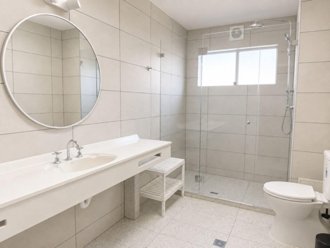 A modern bathroom with a large mirror, a sink, a shower, and a toilet.