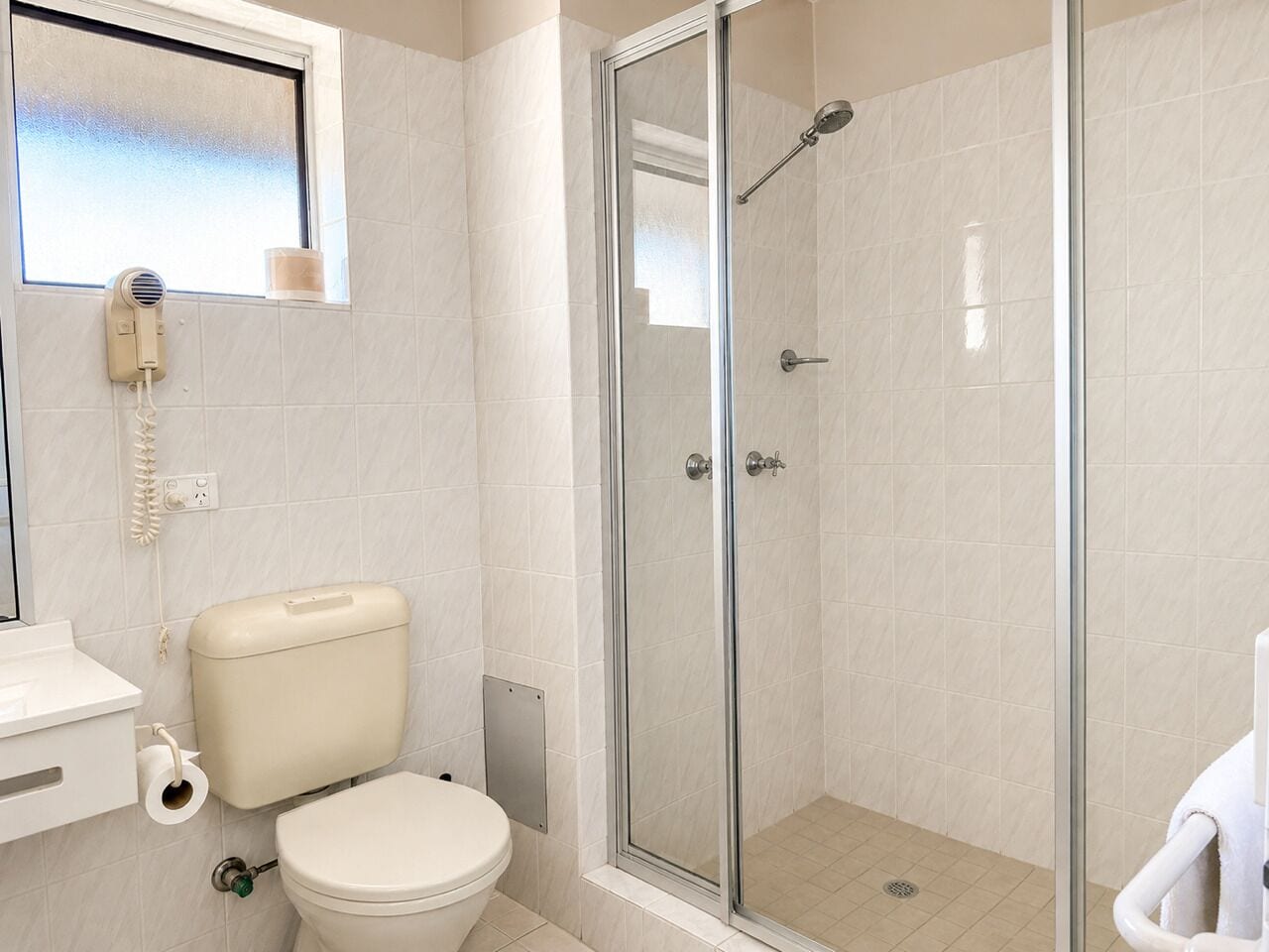 Un baño con inodoro, ducha con cerramiento de vidrio y lavamanos blanco.