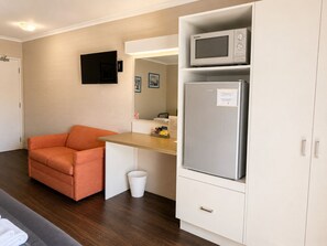 Una kitchenette compacta con microondas, refrigerador y una pequeña mesa.