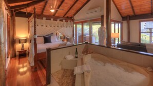 A bedroom with a four-poster bed, a sitting area with a bathtub, and a view of the outdoors. - Misty View Cottages Montville (Montville)