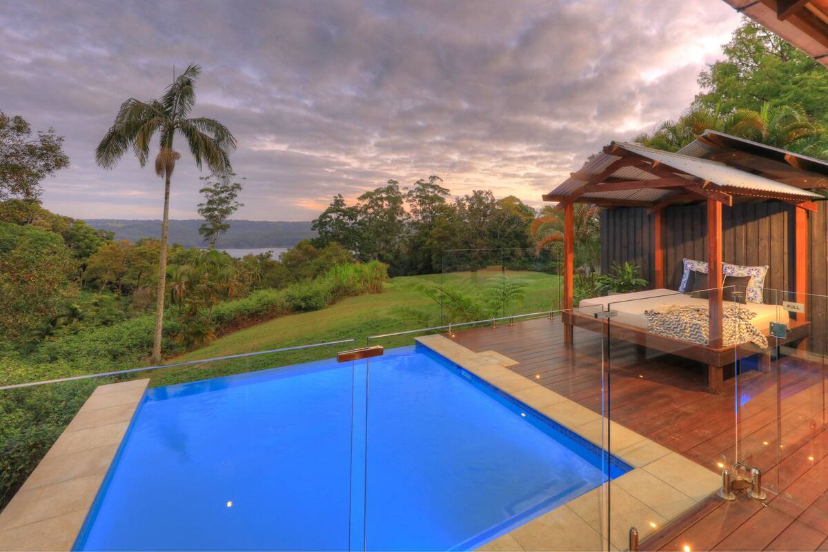 Ein Schlafzimmer mit einem verglasten Balkon, einem Pool und Blick auf die Landschaft.