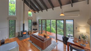 A spacious living area with a fireplace, large windows, and a dining area with a view. - Misty View Cottages Montville (Montville)