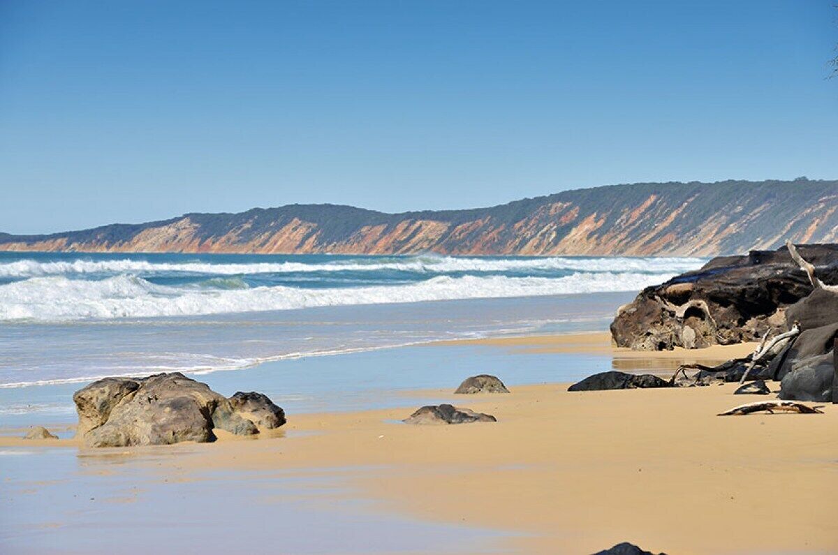 A beach with large rocks and a clear view of the ocean.