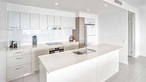 A modern kitchen with white cabinetry, a large island with a sink, and built-in appliances.