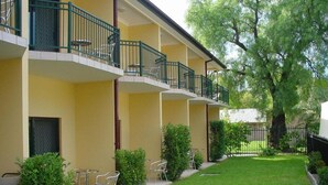 Un edificio de varios pisos con balcones, mobiliario exterior y un césped bien cuidado.