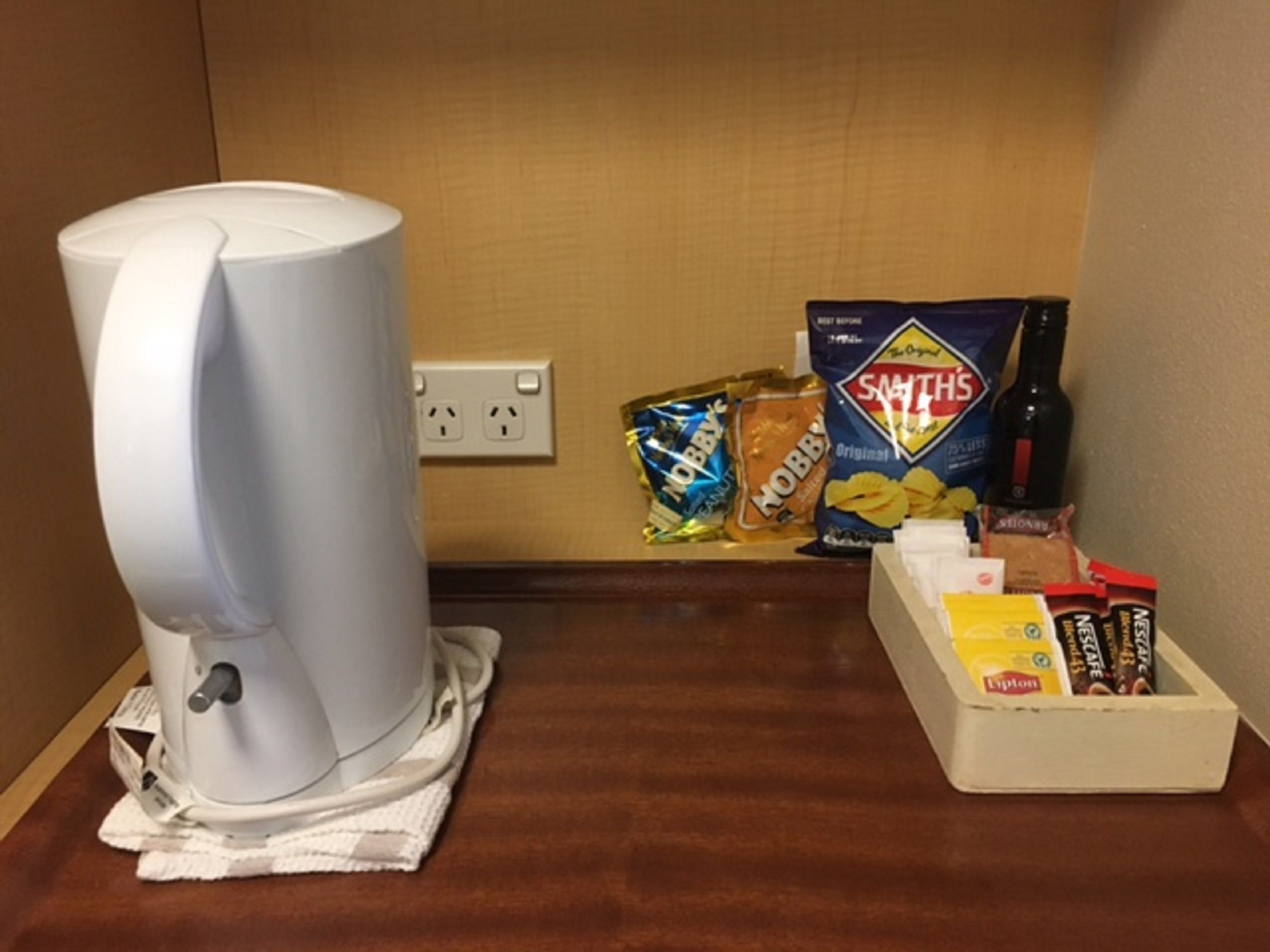 Een koffiezetapparaat op een tafel met lekkernijen en een doos Lipton thee.