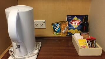 En kaffemaskine på et bord med snacks og en kasse Lipton te.