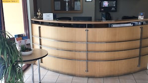 Un mostrador de recepción con un reloj, un televisor y un cartel de precaución.