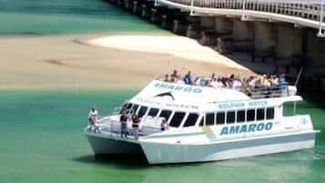 A boat named 'AMAROO' with passengers, docked near a bridge and waterfront.
