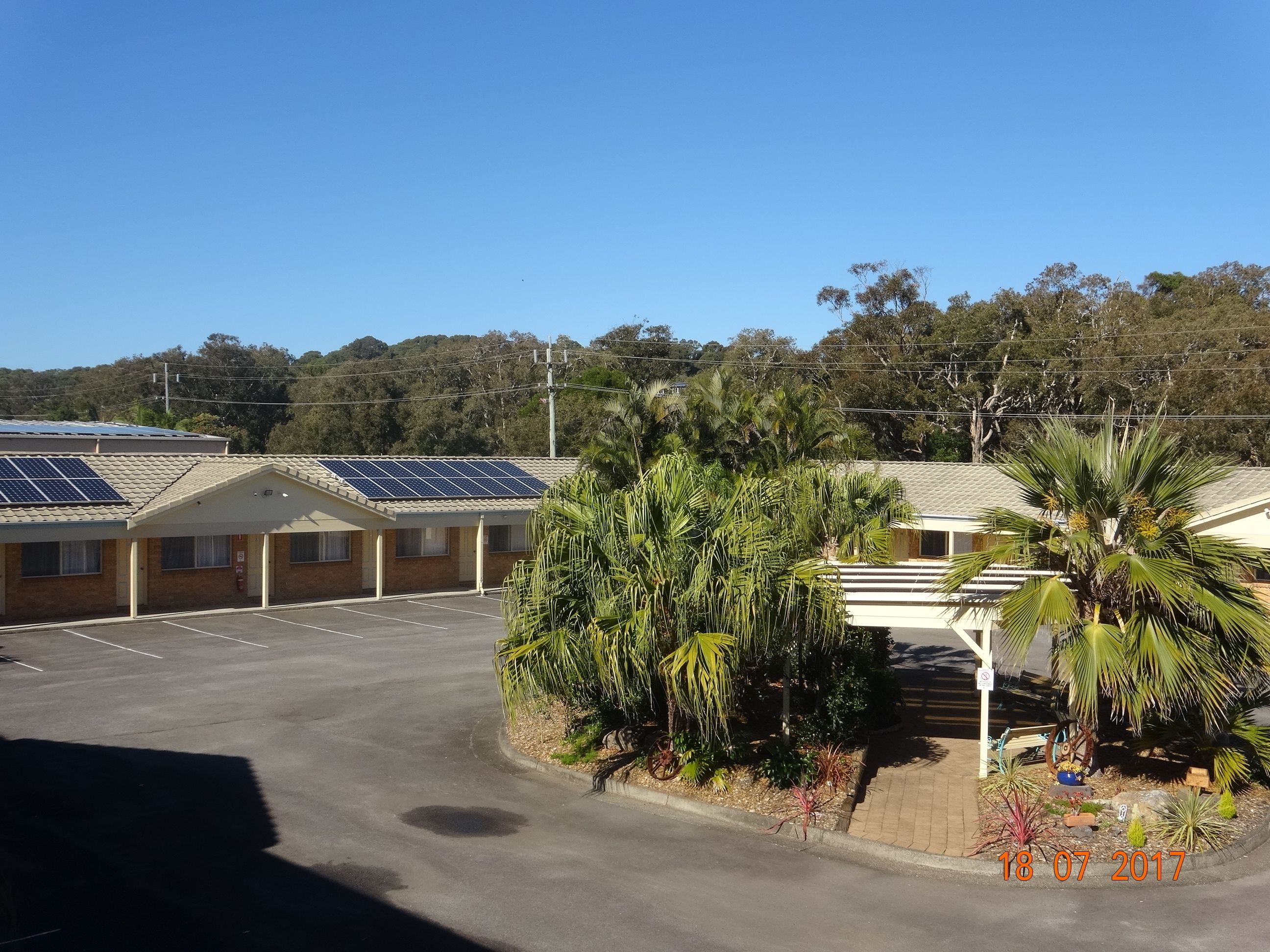 Un motel doté de panneaux solaires sur les toits, d’un parking et d’une variété de plantes tropicales.