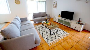 A living room with a sofa, a coffee table, a TV, and a cabinet. - Tweed Harbour Motor Inn (Tweed Heads)