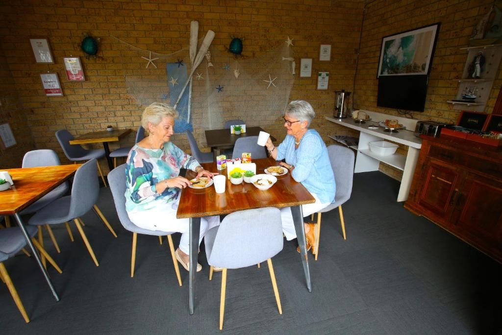 Et spiseområde med murstensvægge, et træbord og grå stole.
