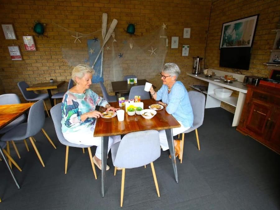 A dining area with brick walls, a wooden table, and grey chairs.