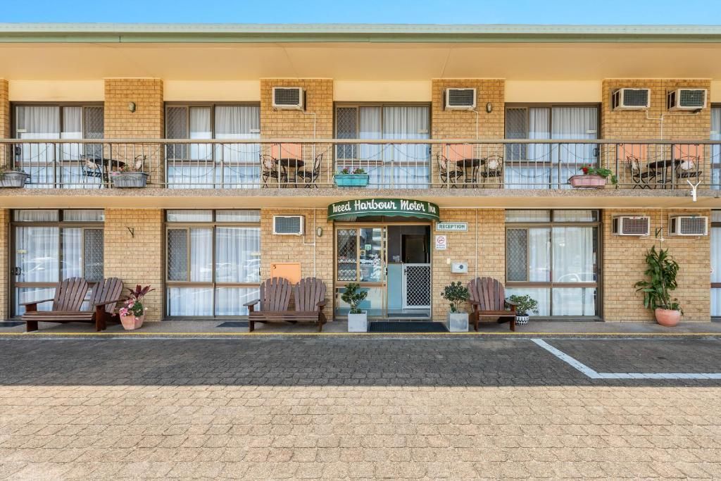 A two-story motel with a brick facade, a reception desk, and outdoor seating.