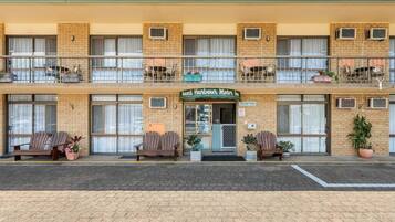 A two-story motel with a brick facade, a reception desk, and outdoor seating.