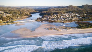 Vue aérienne d’une zone côtière avec un pont, une plage de sable et une rivière.