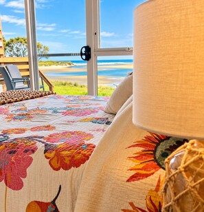 A bed with a floral-patterned bedspread, a beige pillow, and a lamp with a woven base.