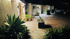 Une allée pavée mène à un bâtiment doté d’un espace d’accueil, qui est entouré de plantes en pot.