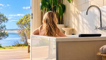 A bathroom with a view of the sea, a bathtub, and a sink.