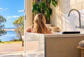 Un baño con vista al mar, una bañera y un lavabo.
