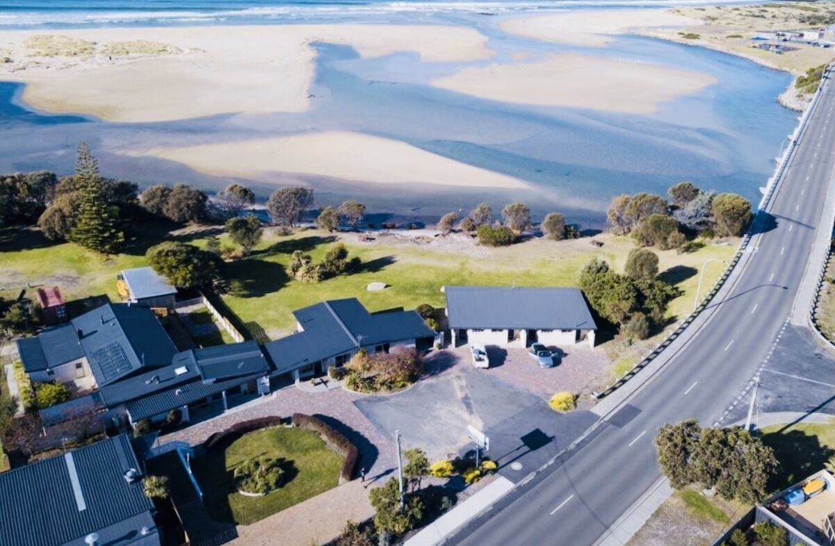An aerial view of a coastal property with a road, beach, and buildings.