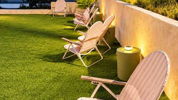 A patio with outdoor furniture and a view of the sea.