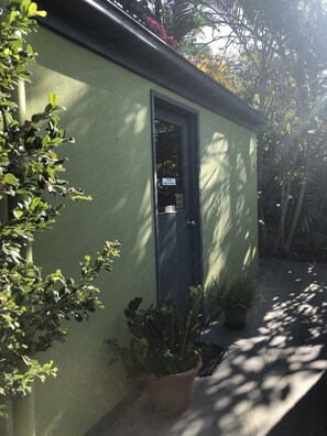 A small building with a green exterior, a dark door, and potted plants around it. - Serenity on Magnetic (Picnic Bay)