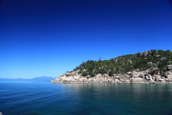 A coastal landscape with a rocky shoreline and calm sea. - Serenity on Magnetic (Picnic Bay)