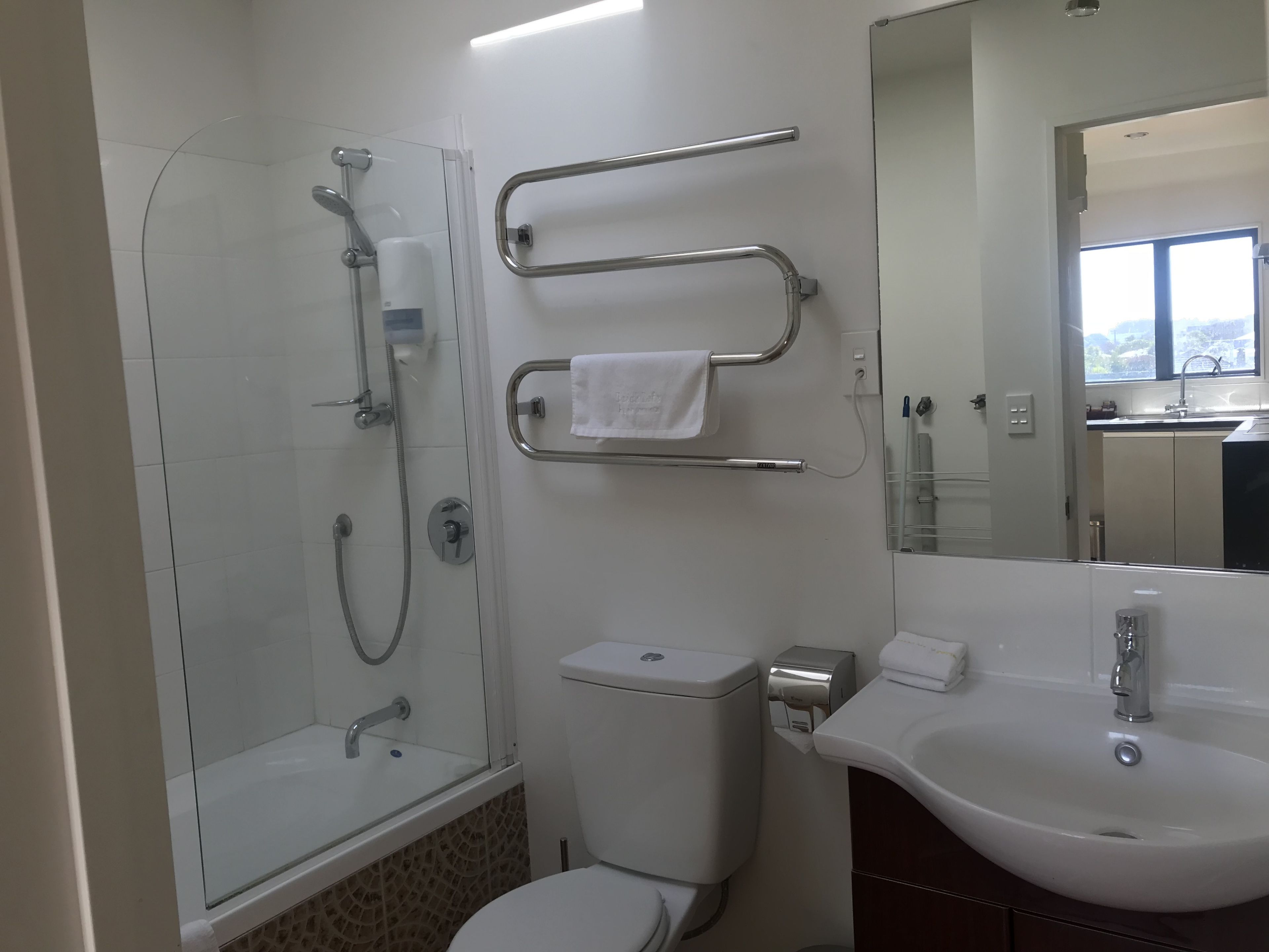 Une salle de bain moderne avec une douche à parois de verre, des toilettes, un lavabo et un miroir.