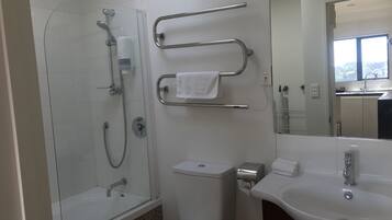 Une salle de bain moderne avec une douche à parois de verre, des toilettes, un lavabo et un miroir.