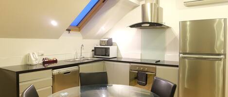 Una cocina moderna con tragaluces, electrodomésticos de acero inoxidable y una mesa de comedor de vidrio.