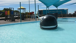 A swimming pool with a large, dark-colored water feature in the center. - Beachlife Apartments (Christchurch)