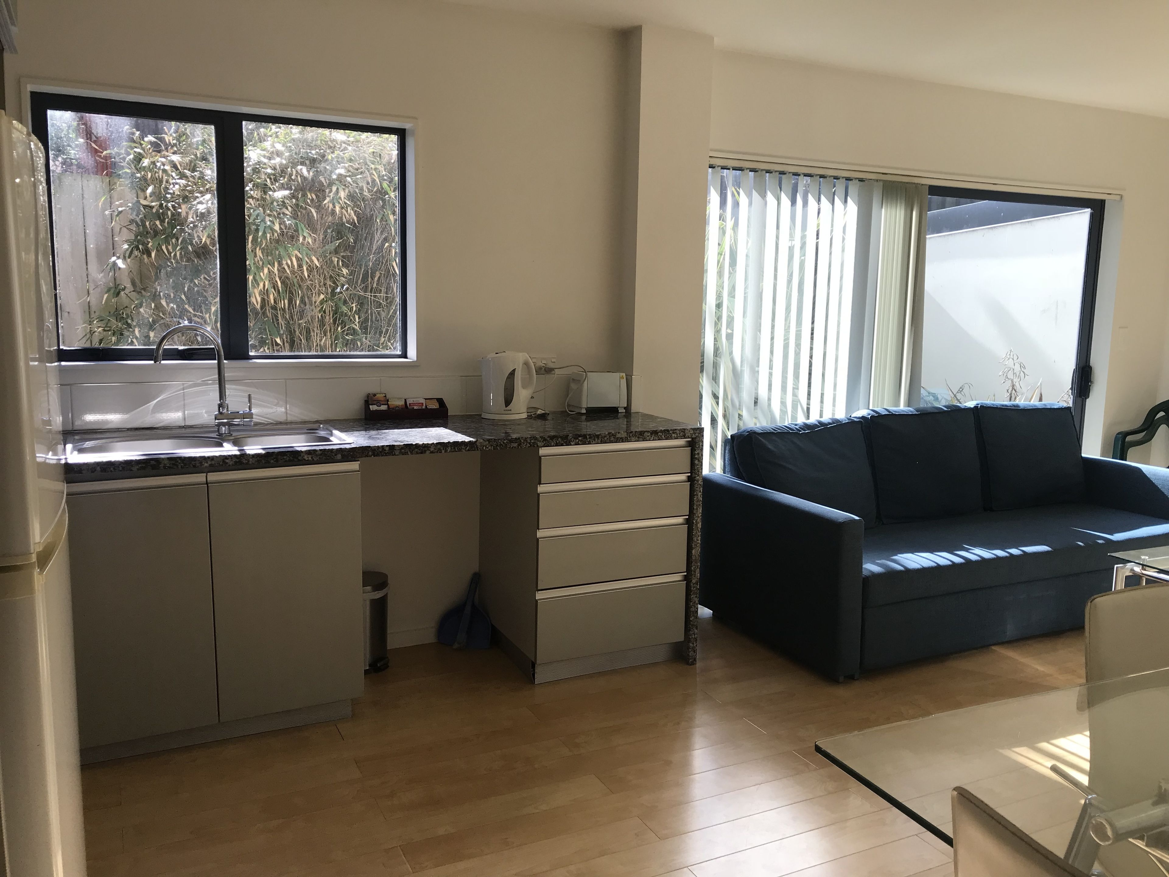 A compact living space with a kitchenette, a sofa, and a large window.