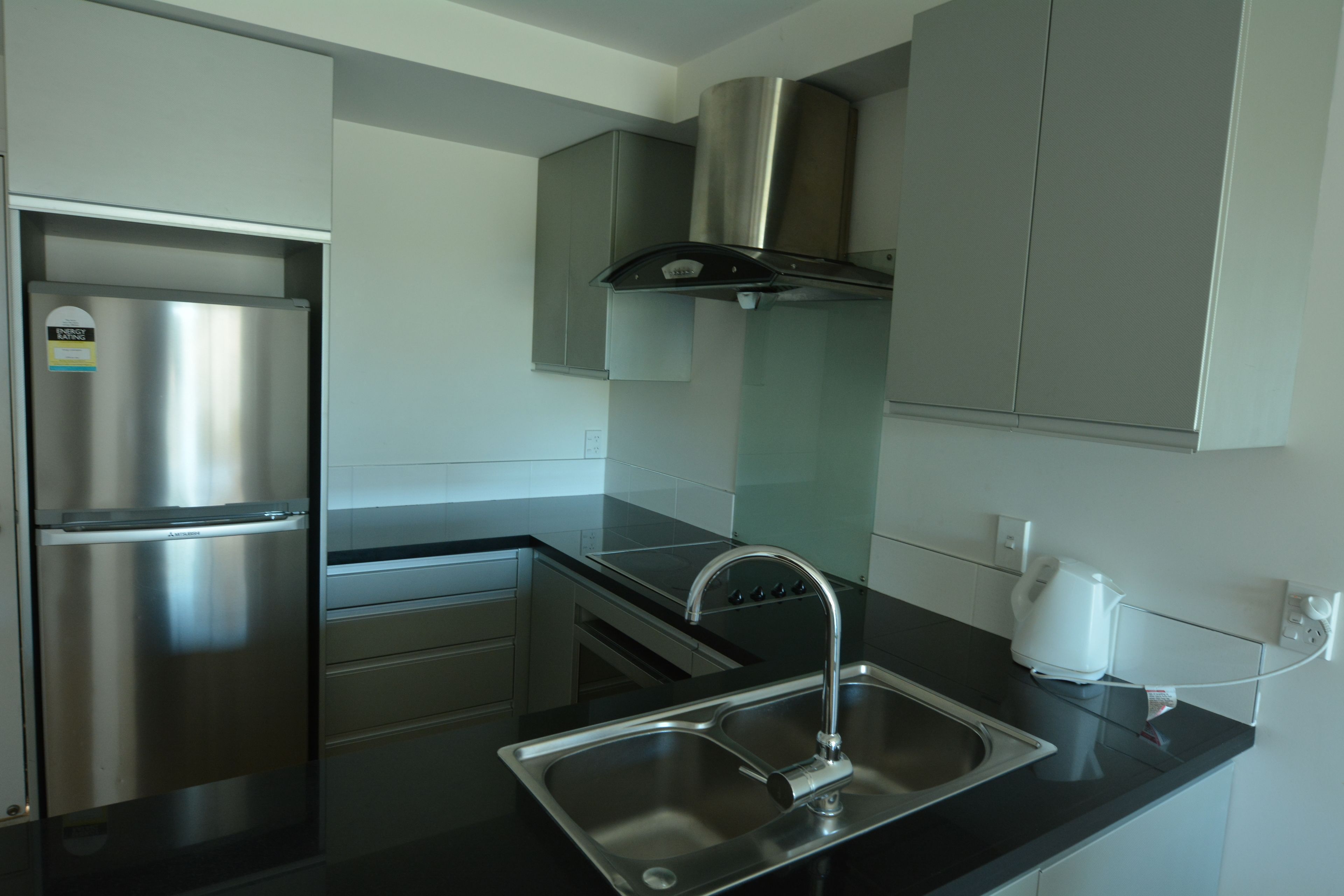 Een moderne keuken met roestvrijstalen apparatuur, een dubbele spoelbak en een gasfornuis.