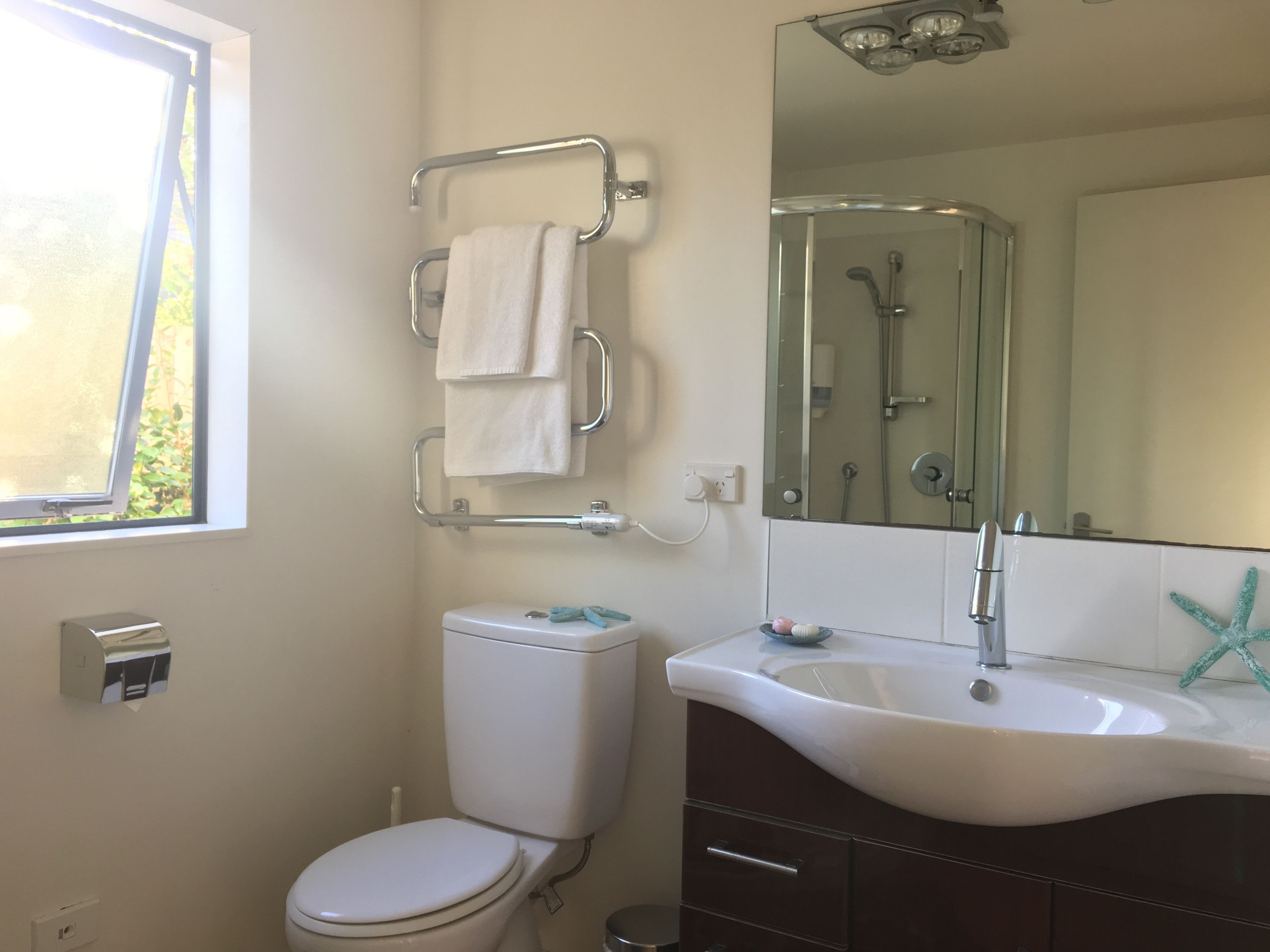 Une salle de bain avec des toilettes, un lavabo, un miroir et une fenêtre.