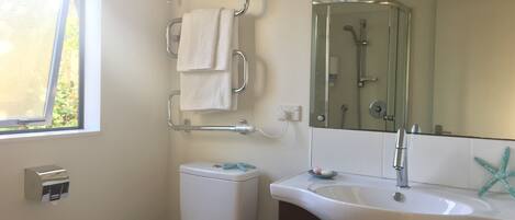 Une salle de bain avec des toilettes, un lavabo, un miroir et une fenêtre.