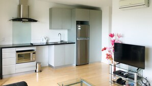 A modern kitchen with a microwave, oven, sink, and stainless steel refrigerator. - Beachlife Apartments (Christchurch)