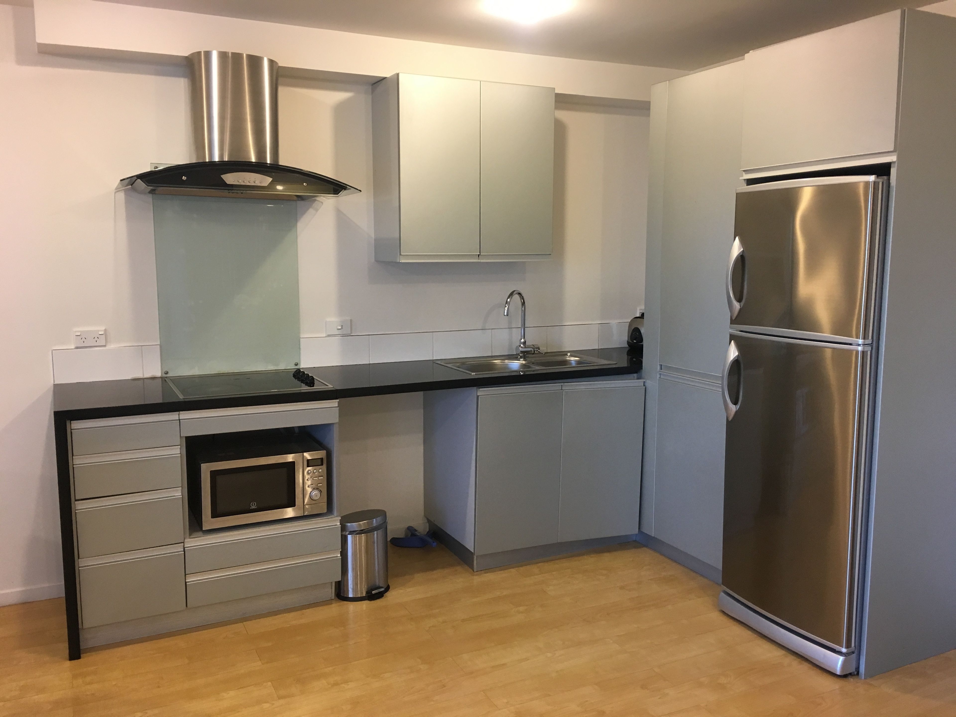 A modern kitchen with a stainless steel refrigerator, a built-in oven, and a microwave.
