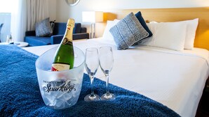 A hotel room with a bed, a blue blanket, a champagne bottle in a bucket, and two wine glasses. - Manly Marina Cove Motel Brisbane (Manly)