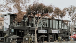 A modern building with a sign for 'San Remo Hotel & Motel' featuring a sports bar, a bistro, and a tab. - San Remo Hotel Motel (San Remo)