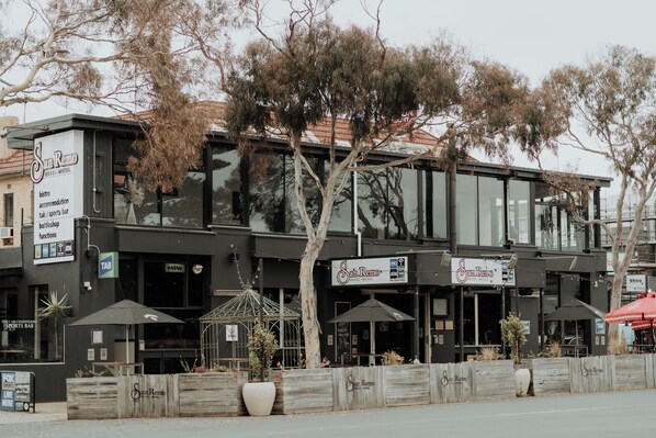 A modern building with a sign for 'San Remo Hotel & Motel' featuring a sports bar, a bistro, and a tab. - San Remo Hotel Motel (San Remo)