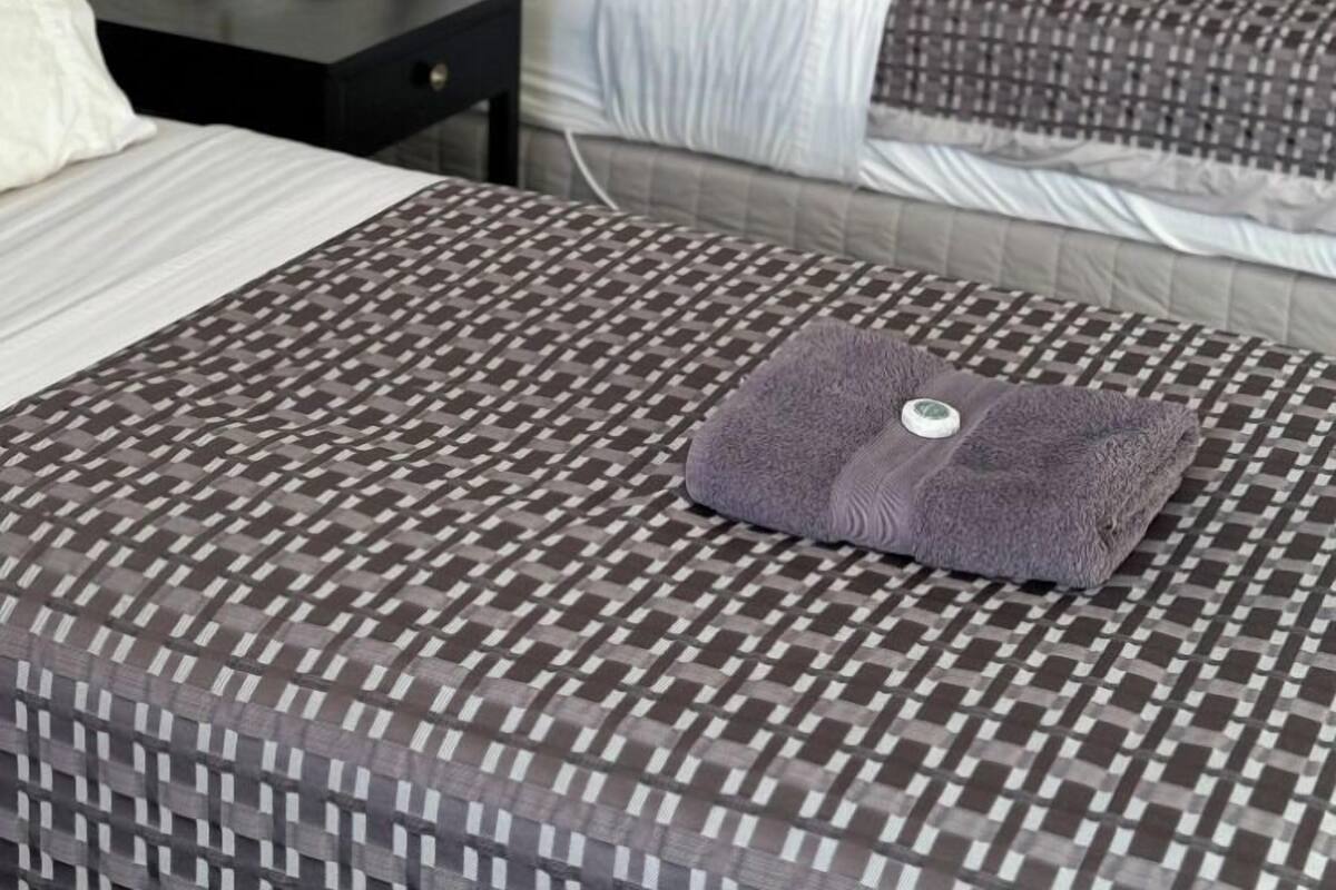 A hotel room with two beds, a nightstand, a lamp, and a framed picture on the wall.