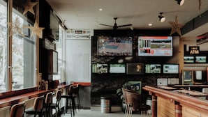 A bar area with wooden bar counters, multiple screens displaying sports, and a sign for 'FOOTY TIPPING'. - San Remo Hotel Motel (San Remo)