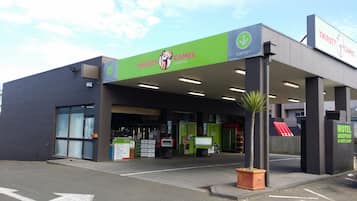 Un edificio con un letrero verde y blanco que indica 'Thirsty Camel Bottleshop' y un letrero que dice 'Recepción Motel'.
