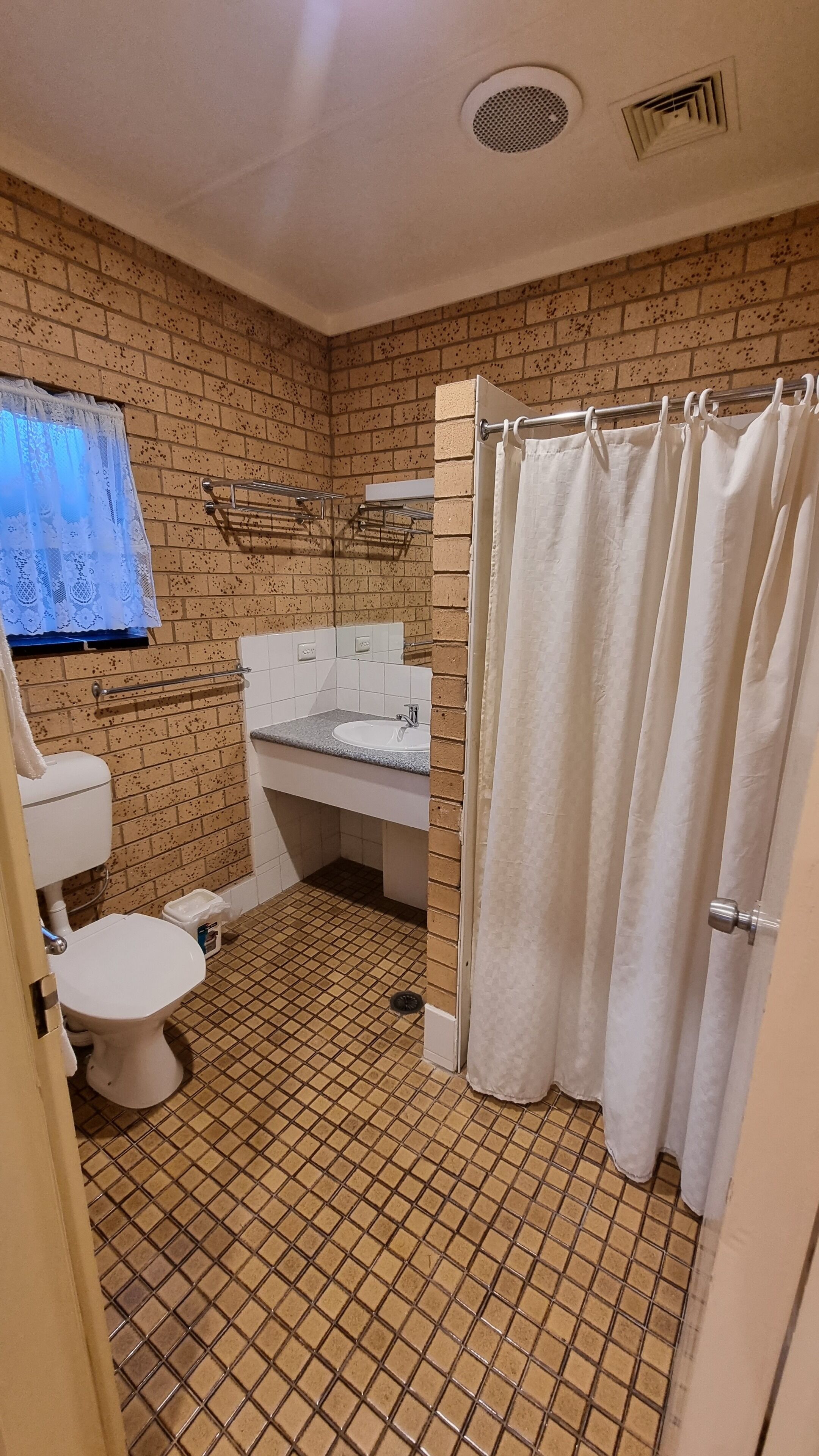 Een badkamer met toilet, wastafel en douchegordijn.