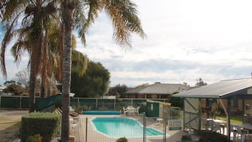 Una piscina al aire libre, sillones reclinables de piscina