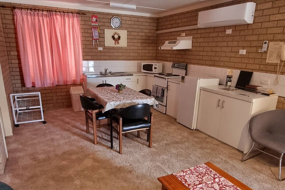 Een knus woongedeelte met een kitchenette, een eethoek en een zithoek met een bank en een salontafel.